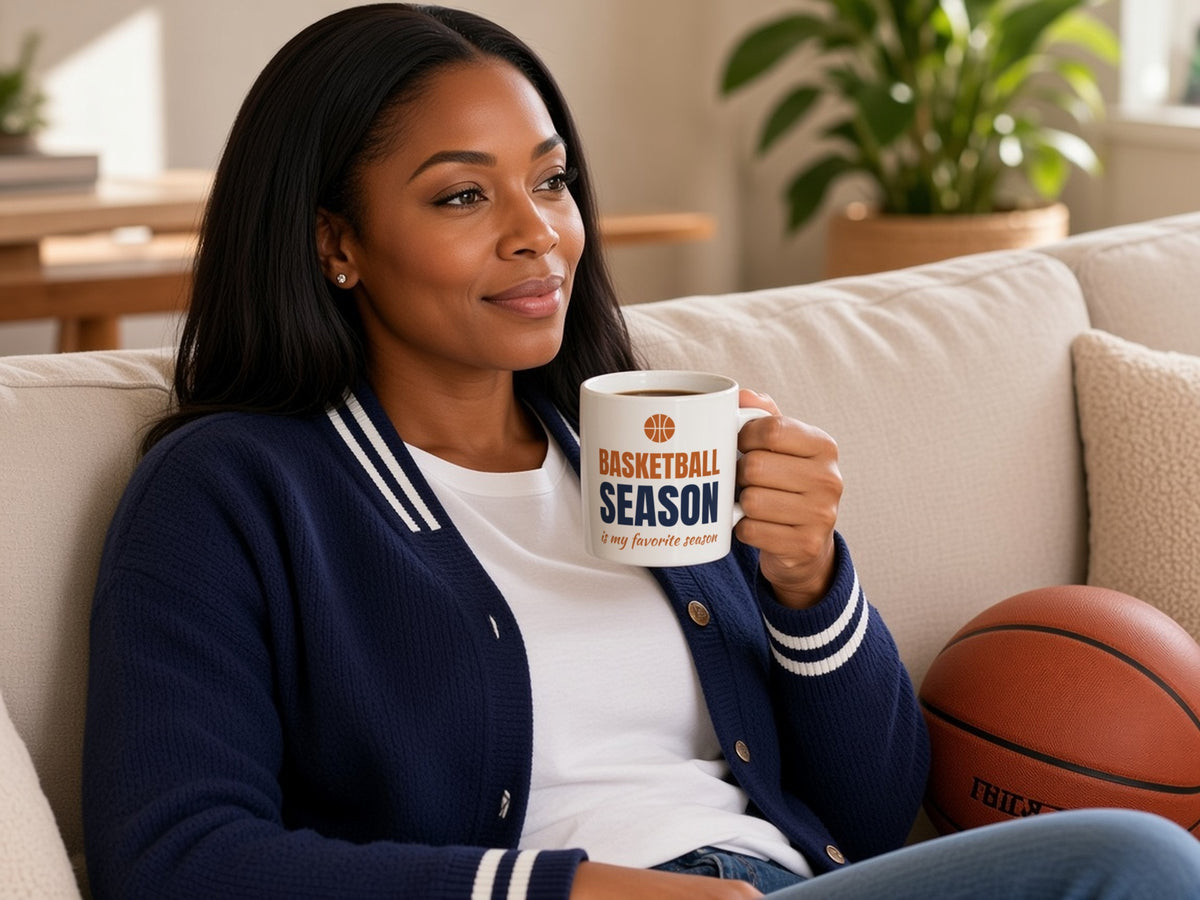 Basketball Season Is My Favorite Season Mug, Basketball Fan Coffee Mug, woman in a navy varsity cardigan holding the mug on the sofa next to a basketball